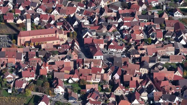 Aerial view of closely packed buildings and a church creating a dense urban fabric with red tile roofs, Rouffach, Grand Est, France.