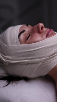 Compression bandages with facelifting effect, facial spa treatment of female patient. Anti-aging skincare, professional beauty treatment