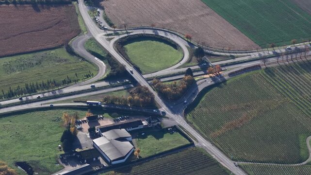 Aerial view of a complex highway intersection, where roads and fields converge creating a tapestry of textures and tones, Rouffach, Grand Est, France.