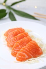 Fresh salmon sashimi with sliced radish on light grey table, closeup