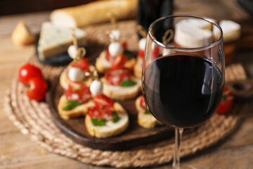 Delicious bruschettas served with red wine on table, selective focus
