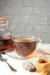 Tasty tea in glass cup, teapot and Turkish desserts on white table against grey textured background, closeup. Space for text