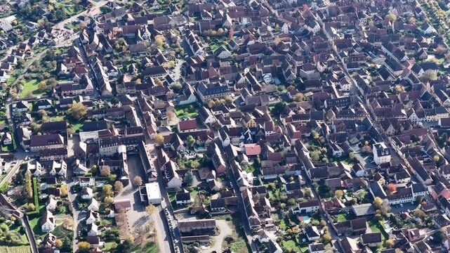 Aerial view of tightly packed houses with red tile roofs, interspersed with trees and narrow streets, create an intricate urban tapestry, Rouffach, Grand Est, France.
