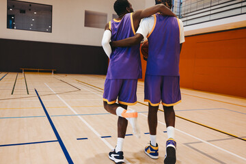 Basketball teammate supporting injured player with sportsmanship and care