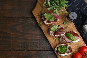 Bruschettas with roast beef served on wooden table, flat lay. Space for text
