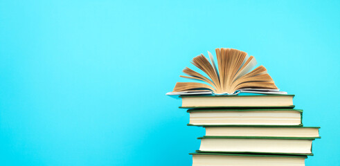 Open book, hardback books on wooden table, on a blue background. Back to school. Copy space for text. Education background. panorama, banner.