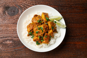 Fototapeta premium Chicken tikka masala with rice served on wooden table, top view