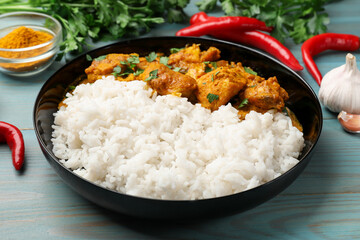 Chicken tikka masala with rice and spices on light blue wooden table, closeup