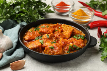 Chicken tikka masala with spices on grey table, closeup