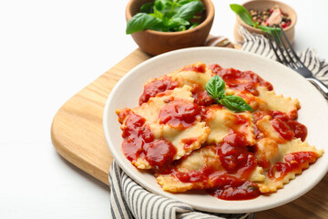 Delicious ravioli with tomato sauce and basil served on white wooden table, closeup. Space for text