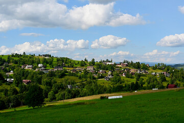 Mountainous rural landscape with hills, fields, trees and residential houses. Podhale, Poland