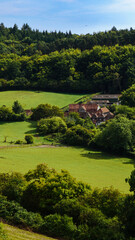 A farmhouse nestled in the valley below the woodlands of Chantry Woods near Guildford, Surrey, on a sunny day.