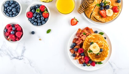 Overhead view of a breakfast spread with pancakes, berries, and bacon.