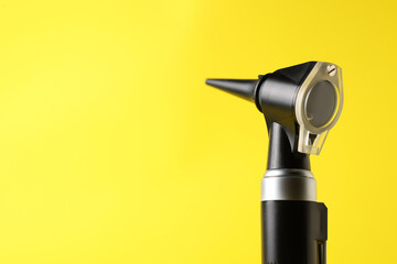 Hearing test. Modern otoscope on yellow background, closeup. Space for text