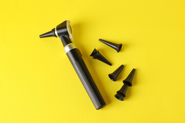 Hearing test. Modern otoscope and ear speculums on yellow background, flat lay