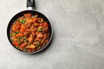 Delicious cooked stew in frying pan on grey table, top view. Space for text