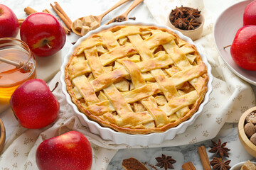 Tasty homemade apple pie and ingredients on white marble table