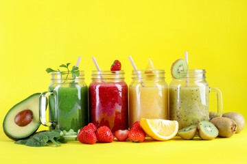 Different tasty smoothies in mason jars and ingredients on yellow background