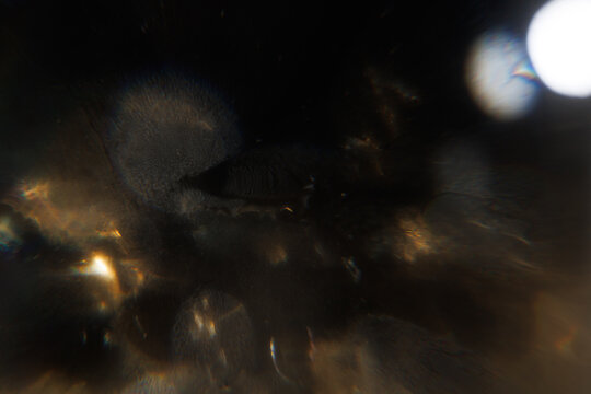 Easy to add lens flare effects for overlay designs or screen blending mode to make high-quality images. Abstract sun burst, digital flare, iridescent glare over black background. Defocused dark bokeh.