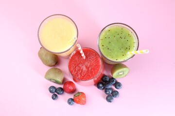 Different tasty smoothies in glasses and ingredients on pink background, flat lay