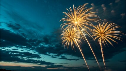 A dazzling night sky illuminated by golden-yellow fireworks bursting in radiant patterns. Their glowing trails and vibrant light contrast beautifully with the deep blue and teal hues of the evening sk