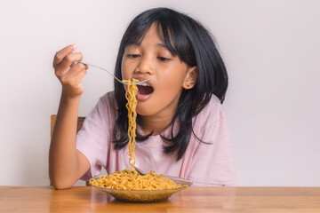 A little girl enjoying a plate of fried noodles at home