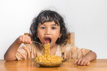 A little Asian girl with curly hair eating fried noodles. Enjoying fried noodles.