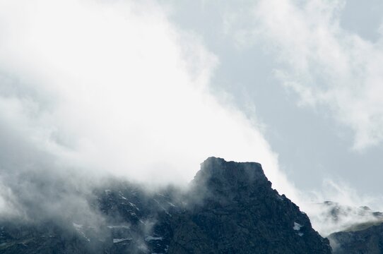 Misty clouds spilling over a rocky mountain ridge
