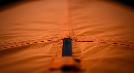 Macro View of Orange Fabric Seam with Black Zipper, Soft Bokeh Background