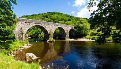 Stone arch bridge over a river, lush green valley