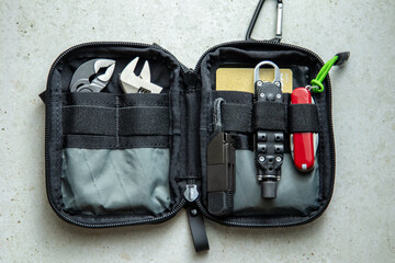 Open EDC pouch with multitool, pliers, knife, lighter and compact tools organized in mesh and elastic compartments.