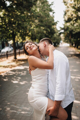 Fototapeta premium Wedding photo of happy smiling newlyweds, stylish groom and beautiful young brunette bride, hugging outdoors on the street in the city, in the park.