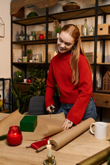 Young woman enjoys cozy moments at home while wrapping a gift for a special occasion
