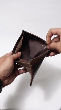 A worn brown leather wallet opened by two hands, revealing no cash inside.