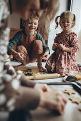 A mother and her children are having a good time in the kitchen. The daughter and son are helping their mother cook.