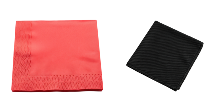 Red coral cocktail napkin with embossed dot pattern next to a folded black cloth pocket square with vertical ribbing isolated on white background table setting