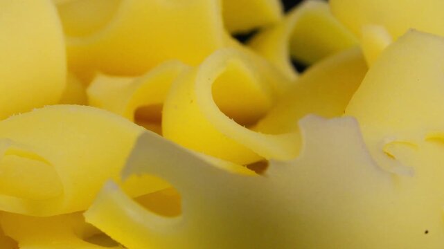 Slices of Emmental cheese on a black rotating background. Slices of Emmental cheese. Macro, close-up. Concept of vegetarianism and healthy eating.