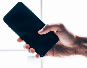 holding black smartphone tilted slightly left