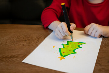 A girl draws a Christmas tree with a marker