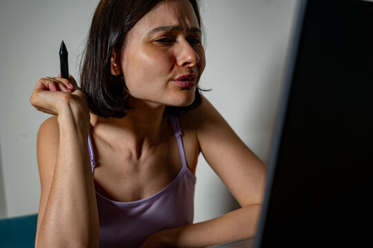 Female retoucher with stylus looking frustrated at laptop