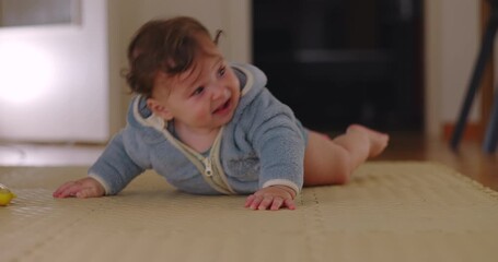 Baby lying sideways on floor resting after attempting to crawl, showing frustration mixed with tiredness and calm expression indoors