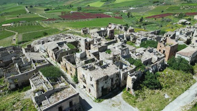 Aerial drone footage of old Poggioreale, Sicily: abandoned ghost town destroyed by the 1968 earthquake, surrounded by hills and silence. Ideal for history, decay, and documentary projects.