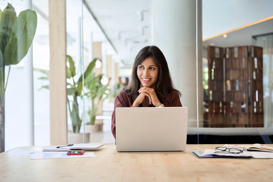 Latin hispanic business woman financier manager working on laptop computer in office, looking at copy space. CEO businesswoman professional employee or young student studying using pc at workplace.