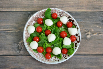 Fresh Caprese Salad with Mozzarella and Cherry Tomatoes on Wooden table flat lay