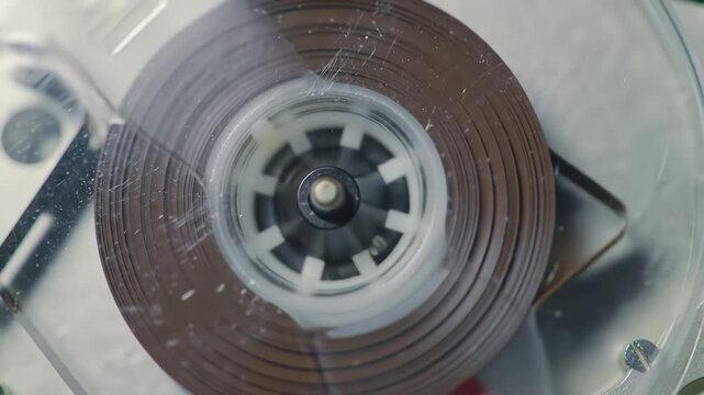 Closeup of a vintage audio cassette tape reel spinning inside a retro player showcasing the classic brown magnetic tape moving as music or sound is played or recorded evoking nostalgia for analog tec. - Powered by Adobe