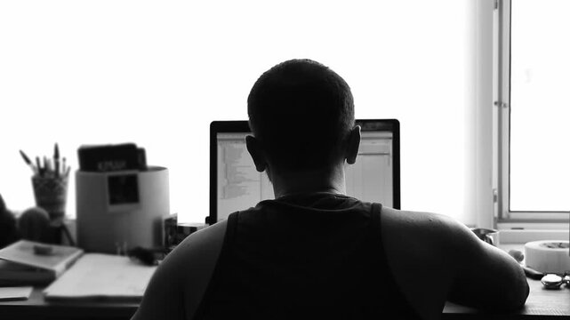 Man Working on Laptop, Back View, black and white. businessman or developer working intensely on a laptop computer, viewed from the back