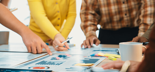 A team of professionals collaboratively analyzing data reports displayed on a table, focusing on...