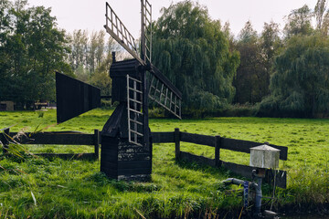 Traditional wooden meadow mill for polder drainage at the Middel in Westzaan, with a nearby Vopo...