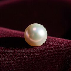 A single, luminous white pearl with a soft sheen resting on a rich, dark red velvet cloth.