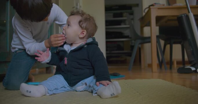 Older brother gently wiping baby brother&rsquo;s nose with tissue, tender sibling care and affection, concept of family love, nurturing, childhood innocence, and brotherly bond